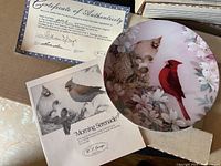 Collector plate titled 'Morning Serenade' displayed in original box alongside its certificate of authenticity, showing detailed artwork of birds and flowers.