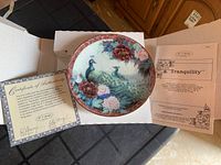 Collector plate with peacock and floral design, certificate of authenticity, and collection info leaflet.
