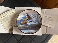 Top view of 'The Return Home' collector plate, showing the bird artwork and accompanying certificate and description card