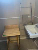 Wooden folding table beside bathroom sink with metallic ladder towel holder.