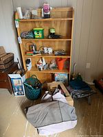 Wide shot of shelving unit with gardening tools, gloves, seed packets, Miracle-Gro container, tapes, spray paint, watering cans, and other supplies.