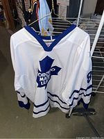 Front view of white Toronto Maple Leafs hockey jersey number 89 Mogilny hanging, showing team logo and blue stripes.