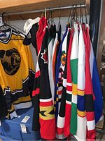 Rack of assorted hockey jerseys in various team colors and a yellow bear-themed jersey