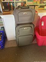 Front and side view showing two grey Air Canada suitcases stacked, with multiple zippered compartments visible on both.