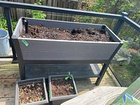 Front view of raised planter on legs with two square pots beneath on deck