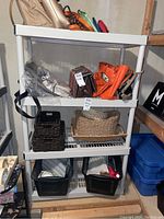Front view of the white plastic shelving unit showing four shelves with various items stored on them (not included in sale).