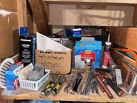Wide view of assorted tools, clamps, caulking tubing, kitchen garbage bags and spray, some screwdrivers and hardware.