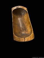 Profile view of carved wooden dough bowl showing elongated trough shape and concave interior
