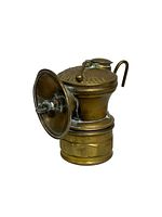Photo showing an antique miners light, brass with a round reflector and hanging hook, measuring approximately 3.5 x 4 inches.