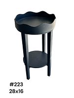 Single front-facing image of a black wooden plant stand with a scalloped edge round tray top and three legs supporting a circular lower shelf, isolated on white background.