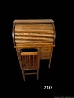 Front view of the child's oak roll top desk with attached chair, showing the closed tambour roll top and two drawers.