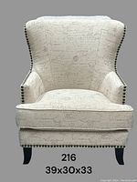 Front view of cream-colored wingback armchair with French script upholstery and nail head trim on edges, standing on dark carved wooden legs. Measurement markings of 39x30x33 inches visible.