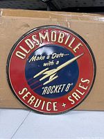 Photo of a 12 inch round metal Oldsmobile Service & Sales sign with Rocket 8 logo and slogan.