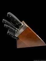 Side view of wood block with three large knives and assorted smaller knives