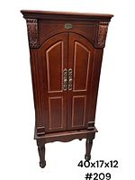 Jewelry armoire cabinet closed showing dark polished wood with decorative carved corners and two doors with handles.
