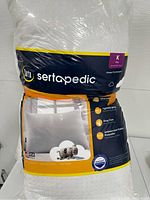 Photo of a Serta king size pillow in its original sealed plastic packaging showing brand and product features.