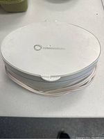 Top view of the closed oval-shaped white sonic jewelry cleaner by Connoisseurs with cord wrapped around the base.