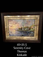 Framed print of Serenity Cove by Thomas Kinkade, showing a coastal lighthouse scene at sunset with detailed frame and plaque.