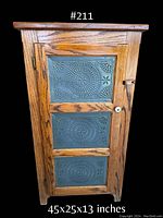 Front view of vintage oak pie safe cabinet with decorative punched metal panels on the door, closed door view, showing wood grain and latch.