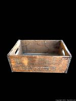 View of the front and side of the weathered wooden beverage storage box showing its exterior surface, dimensions approximately 16x6x12 inches.