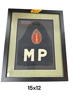 Framed American MP armband on dark fabric with embroidered red and yellow insignia and white 'MP' letters, 15x12 inches.