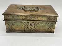 Closed top and front view of engraved brass stationery box showing overall design and patina
