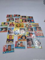 Top view of assorted vintage baseball and football cards spread out on a white surface showing various players and teams.