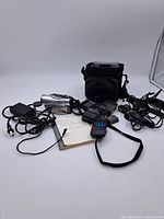 Photo showing Canon Elura 65 camcorder with attached cables, handwritten notes, remote, and carrying case in background