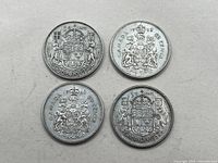 Four Canada silver 50 cent coins showing the detailed reverse heraldic coat of arms design with date 1927, 1950, 1952, and 1963.