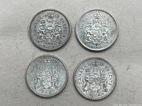 Four Canada silver 50 cent coins laid flat on a light surface, showing details of the Canadian coat of arms and coin dates.
