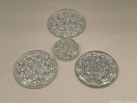 Four vintage clear glass flower frogs of varying sizes arranged on a flat surface for size comparison.