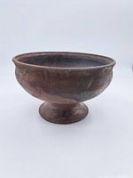 Side profile of large brown ceramic footed bowl showing round shape and pedestal base.