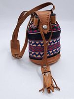 Full view of the vintage bag showing leather strap, flap, and decorative woven fabric body with geometric pattern.