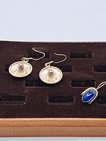 Pair of hallmarked sterling silver earrings and blue stone pendant on brown velvet tray