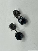 Pair of sterling silver and marcasite drop earrings showing floral stud tops and faceted black bead drops.