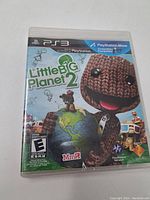 Front cover of Little Big Planet 2 PS3 game case showing colorful artwork with Sackboy character and game title.