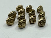 Set of thirteen brass name/place holders showing textured shell-like design and vintage wear.