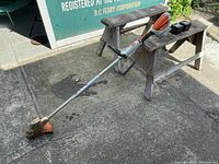 Full view of Stihl FSA 57 cordless string trimmer with two batteries placed on wooden bench