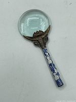 Full view of magnifying glass showing lens, brass mount, and porcelain handle.