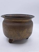 Side view of the vintage metal jardiniere showing rounded body with patina and slight discoloration.