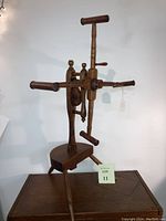 Full view of antique wooden yarn winder showing tripod base and vertical spindle with rotating wheel and handles.