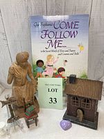 Photo showing all items in the lot including a fairy book, wooden fairy house, wooden statue, sign, chair, purple heart stone, and small wooden stool.