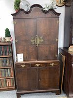Front view of restored walnut cabinet with closed doors showing the grain finish, brass hardware, and design details.