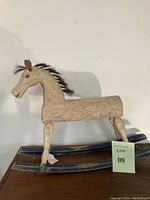 Full side view of the hand-carved rocking horse showing the chalk white paint and blue rockers