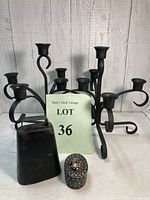 Photo displaying the full set including the pair of black metal candelabra, cow bell, and ornate trinket box, with lot card visible.