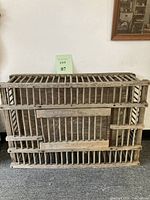 Full view of the rectangular wooden crate lying on its side, showing the construction and slatted walls.