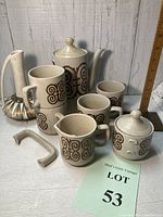 Full view of entire vintage stoneware coffee/tea set with pots, mugs, sugar bowl, and separate decanter bottle without top