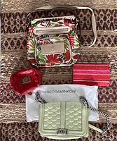 Four purses arranged on a patterned fabric background showing patterned purse, Rebecca Minkoff purse on dust bag, small red pouch, and pink striped item