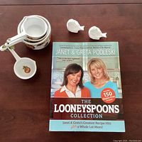 Set of measuring cups, two bird-shaped shakers, and cookbook on tabletop