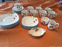Complete 26-piece Royal Albert Fuschia tea set on orange cloth background, showing cups, plates, and serving pieces arranged neatly.